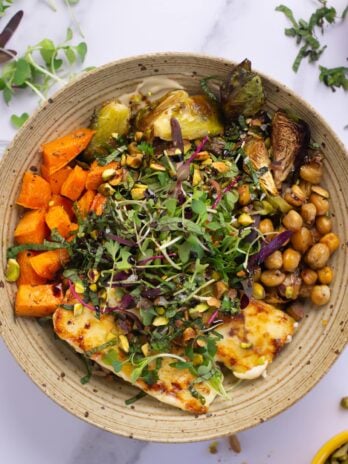 Bowl with creamy cashew sauce, orzo, fried feta, roasted brussels sprouts and chickpeas and sweet potatoes