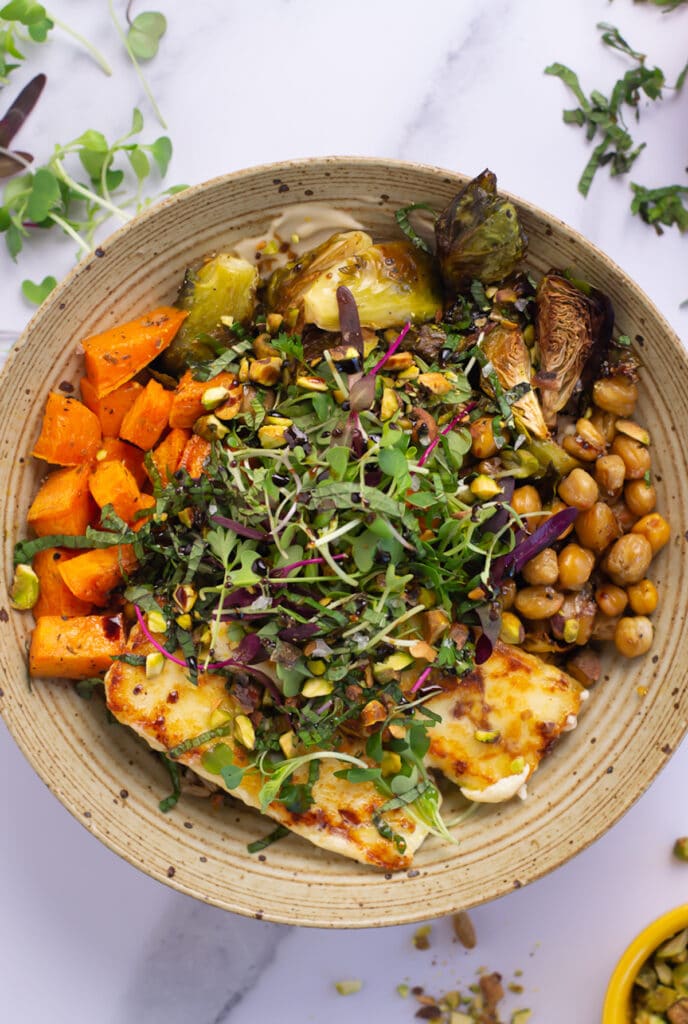 Bowl with creamy cashew sauce, orzo, fried feta, roasted brussels sprouts and chickpeas and sweet potatoes