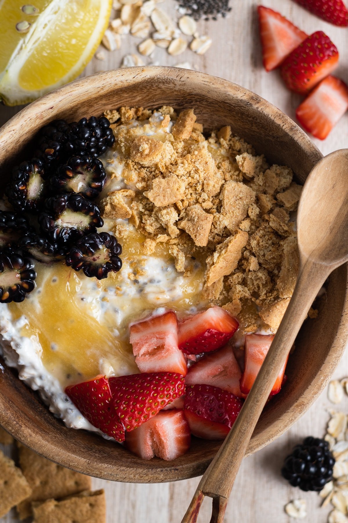 lemon cheesecake overnight oats topped with berries and graham cracker crumbs