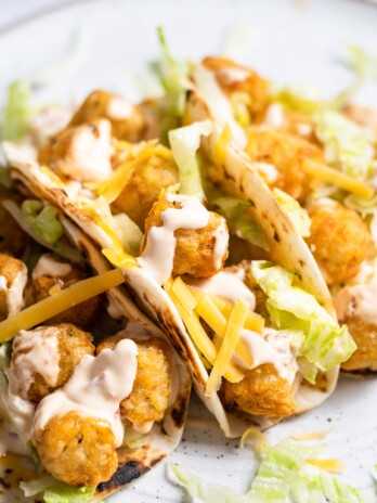 picture of three tacos with tator tots, tortillas, iceberg lettuce cheese and creamy chipotle sauce