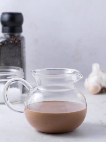 glass teapot filled with fig balsamic dressing with dressing ingredients in the background