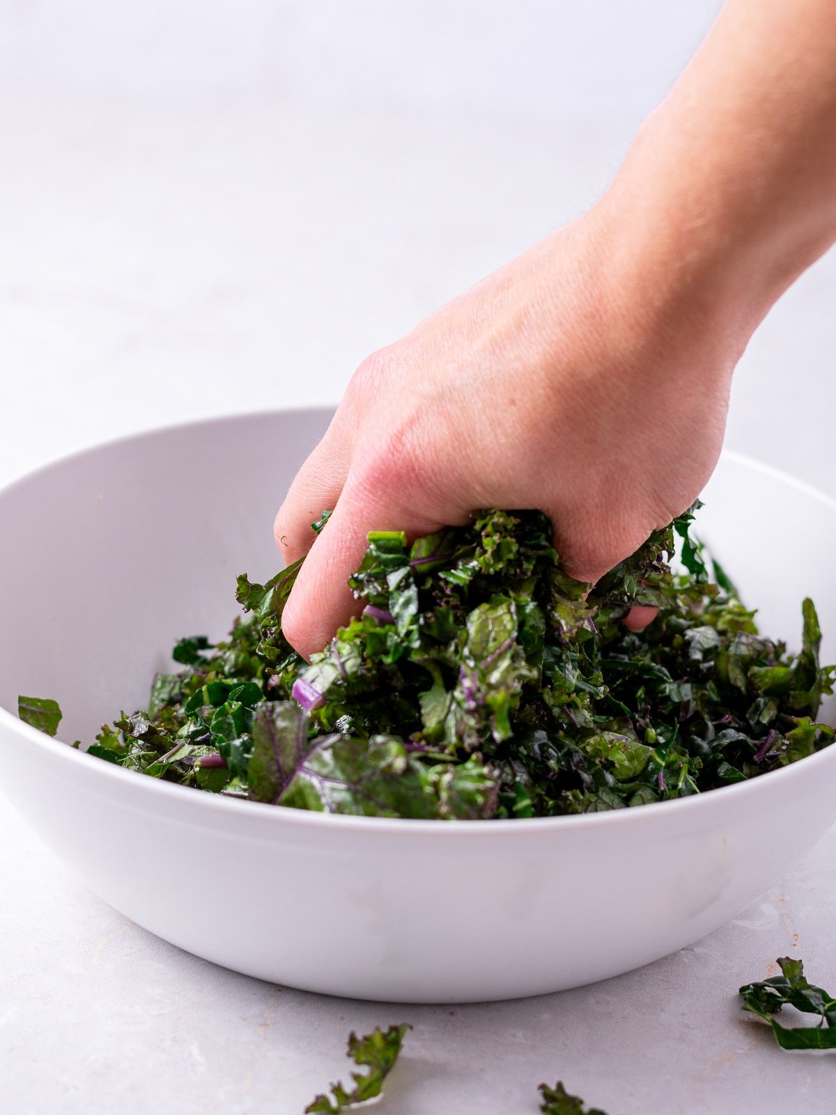 Hand massaging a bowl of kale