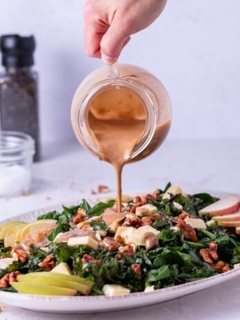 balsamic fig dressing poured onto kale and spinach salad with apples and sharp white cheddar