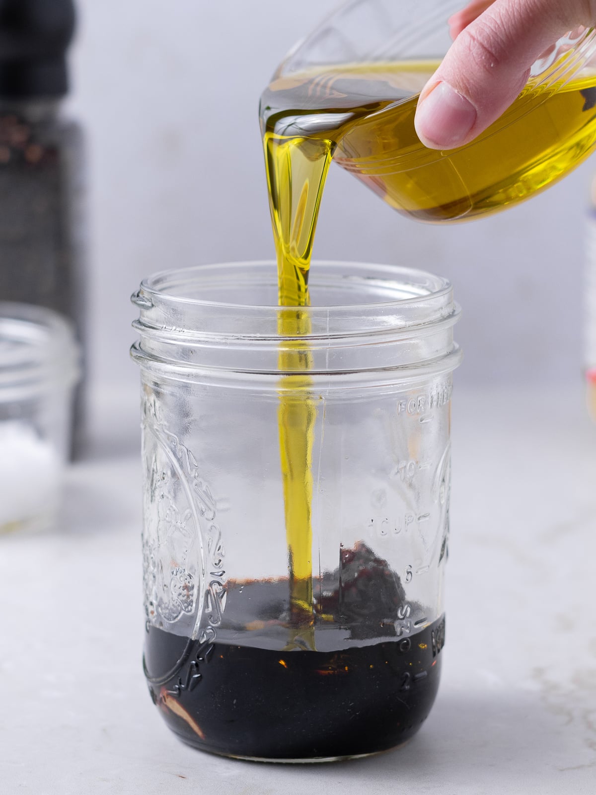 olive oil being poured into the balsamic vinegar