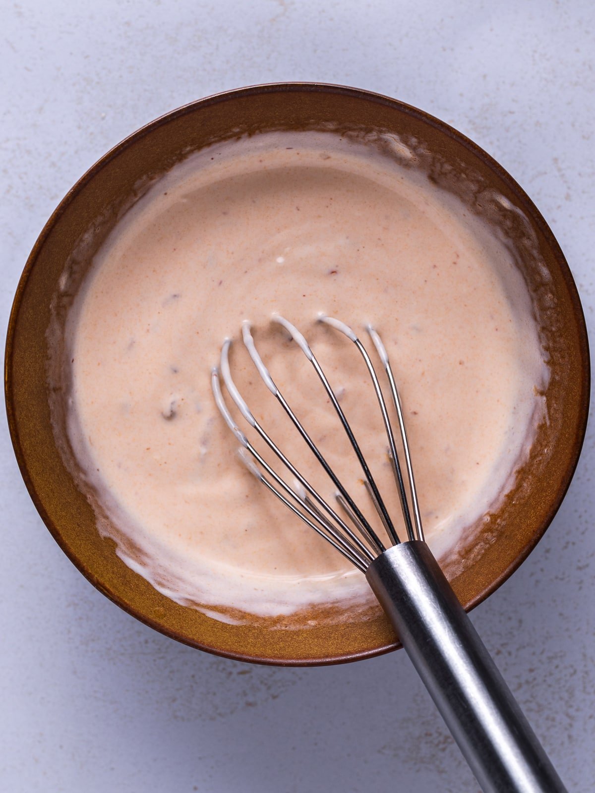 bowl of creamy chipotle lime sauce with a whisk in it