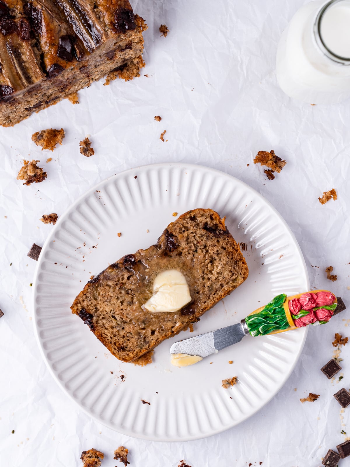 small white plate with a slice of cottage cheese banana bread and pat of melting butter