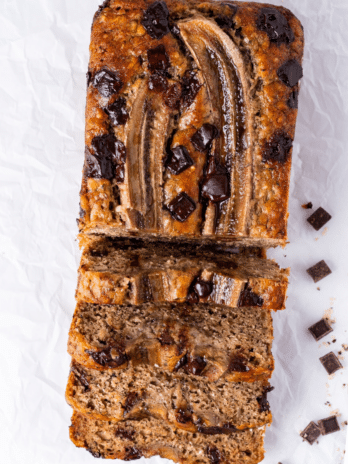 Chocolate chip banana bread loaf sliced to show moist texture and ripe banana topping