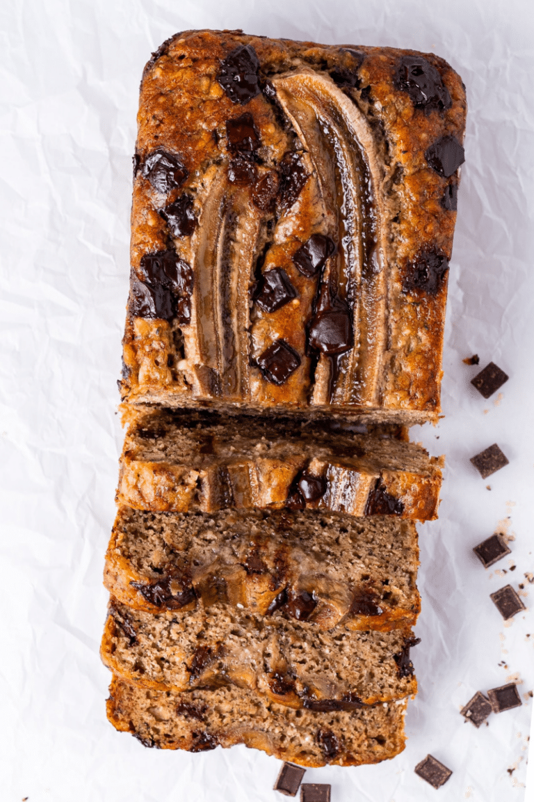 Sliced cottage cheese banana bread topped with banana and chocolate chunks on parchment paper.