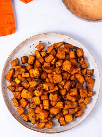 plate with roasted sweet potato cubes, small bowl of harissa aioli