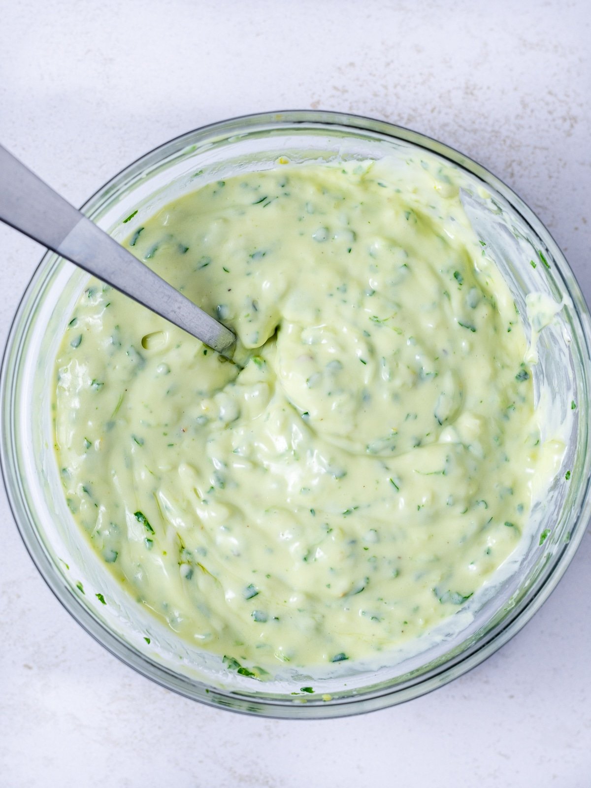 small bowl with creamy chimichurri aioli in it with a spoon