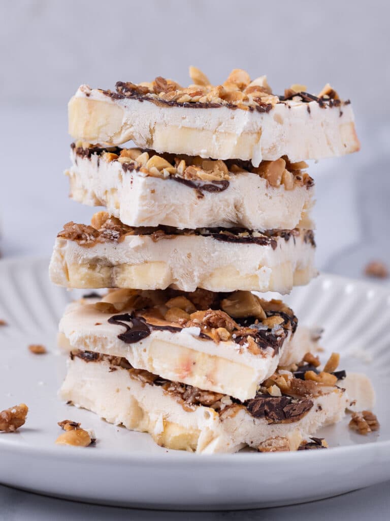 Stack of frozen cottage cheese bark pieces with banana, peanut butter, chocolate and chopped peanuts.