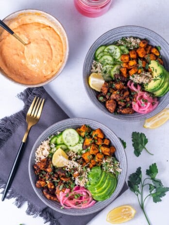 two bowls with honey harissa chicken, rice and toppings