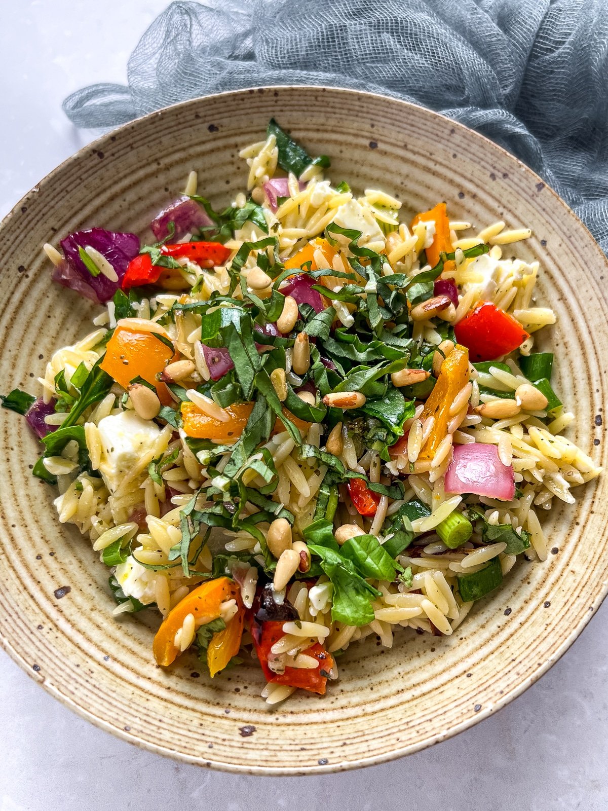 bowl with orzo, roasted vegetables, fresh basil, chunks of feta