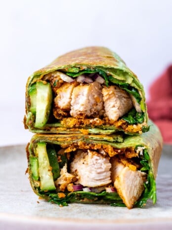 two halves of a chicken hummus wrap stacked on a plate