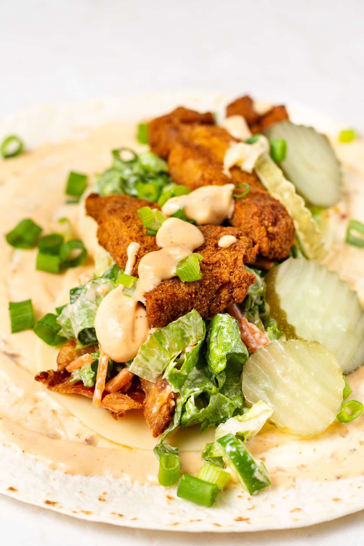 inside of honey mustard chicken wrap- crispy chicken, spicy honey mustard and green leafy lettuce