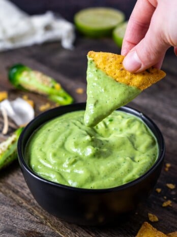 tortilla chip dipped into a small bowl of jalapeño crema