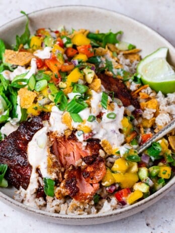 bowl with flaked chipotle salmon, mango pico de gallo, brown rice, shredded lettuce and creamy chipotle sauce