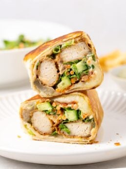 two halves of honey mustard chicken wrap on white plate