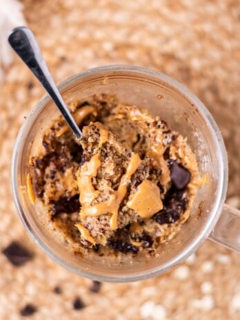 spoon digging into an oatmeal mug cake drizzled with peanut butter