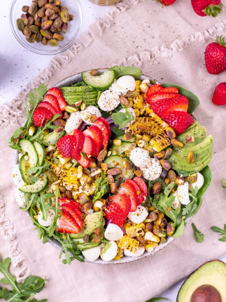 summer salad with spinach, arugula, strawberries, avocado, corn and mozzarella