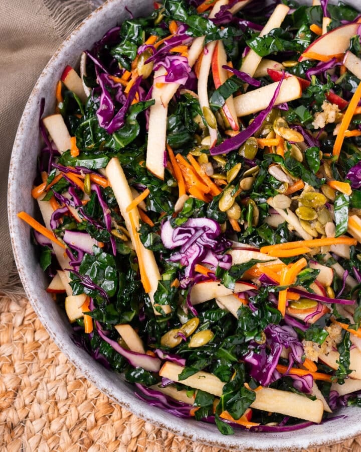 close up view of kale, matchstick apples, julienned carrots, purple cabbage and pumpkin seeds