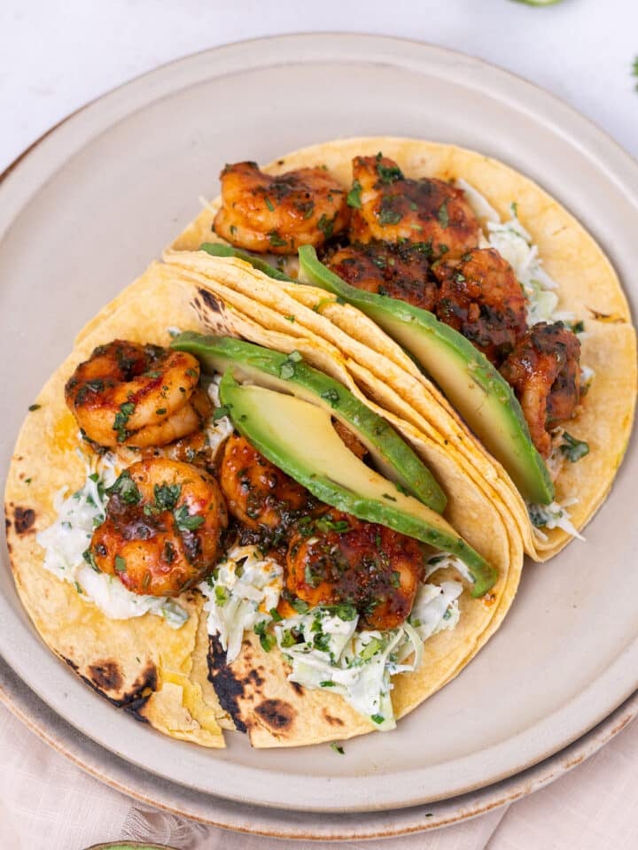 plate with corn tortillas with creamy cilantro slaw, seasoned shrimp and sliced avocado