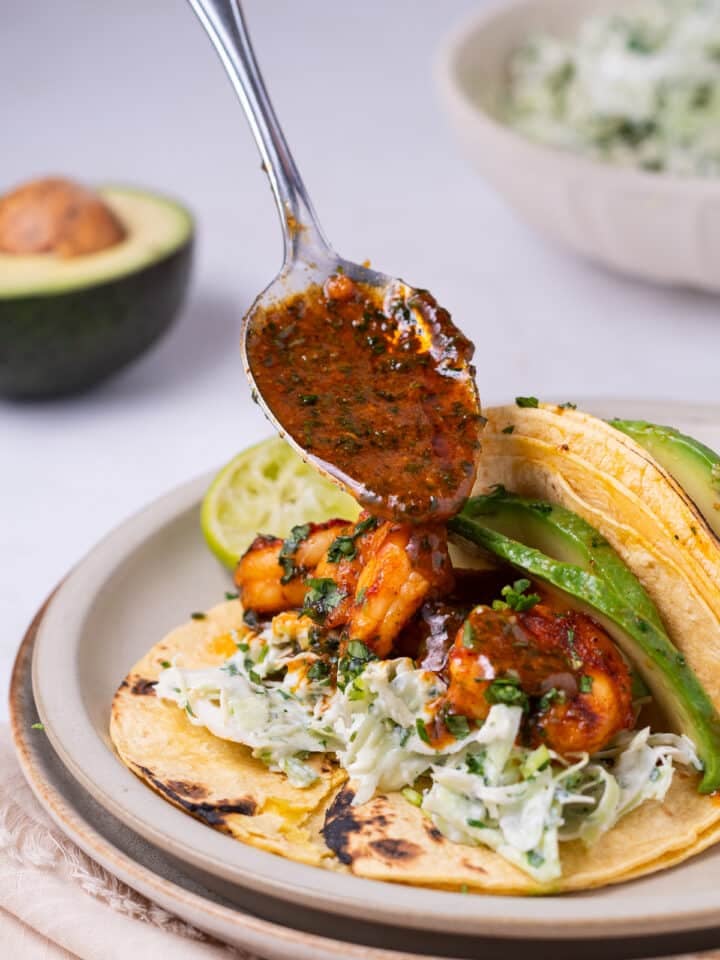 spoon drizzling shrimp with honey lime cilantro sauce