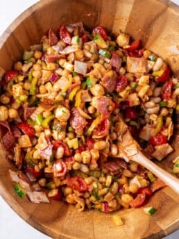 large wooden bowl with dense bean salad and a wooden spoon