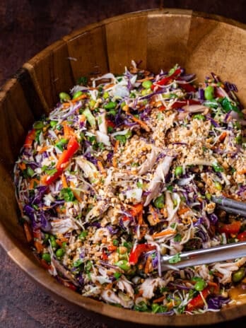 large wooden bowl full of cabbage salad with peanuts and peanut vinaigrette