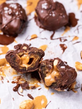 medjool date stuffed with peanut butter and peanuts and covered in chocolate, sliced in half