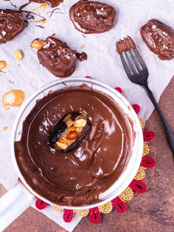 peanut butter filled date in a small saucepan of melted chocolate