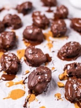 chocolate covered peanut butter stuffed dates on a piece of parchment paper