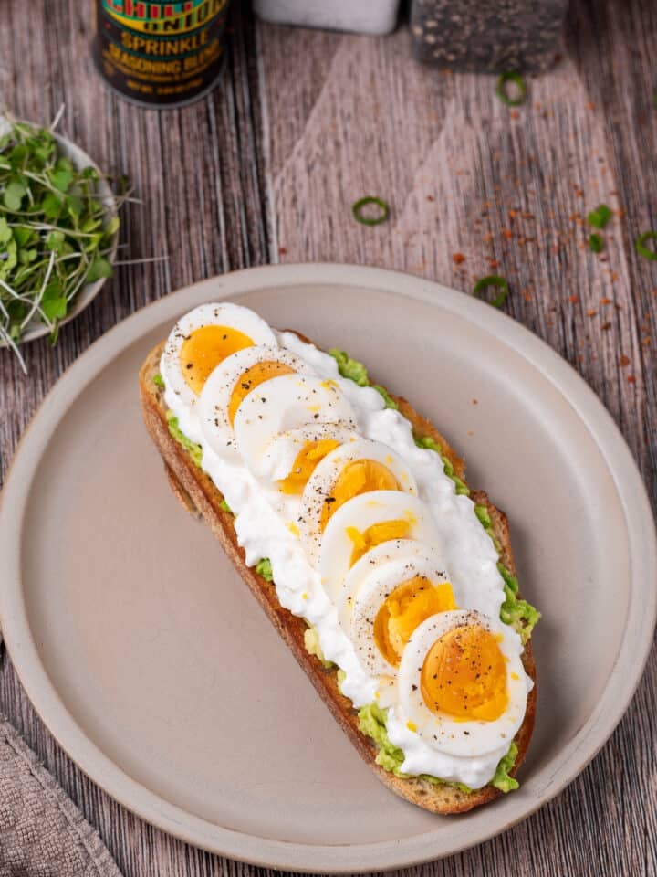sliced medium boiled egg on avocado toast with cottage cheese