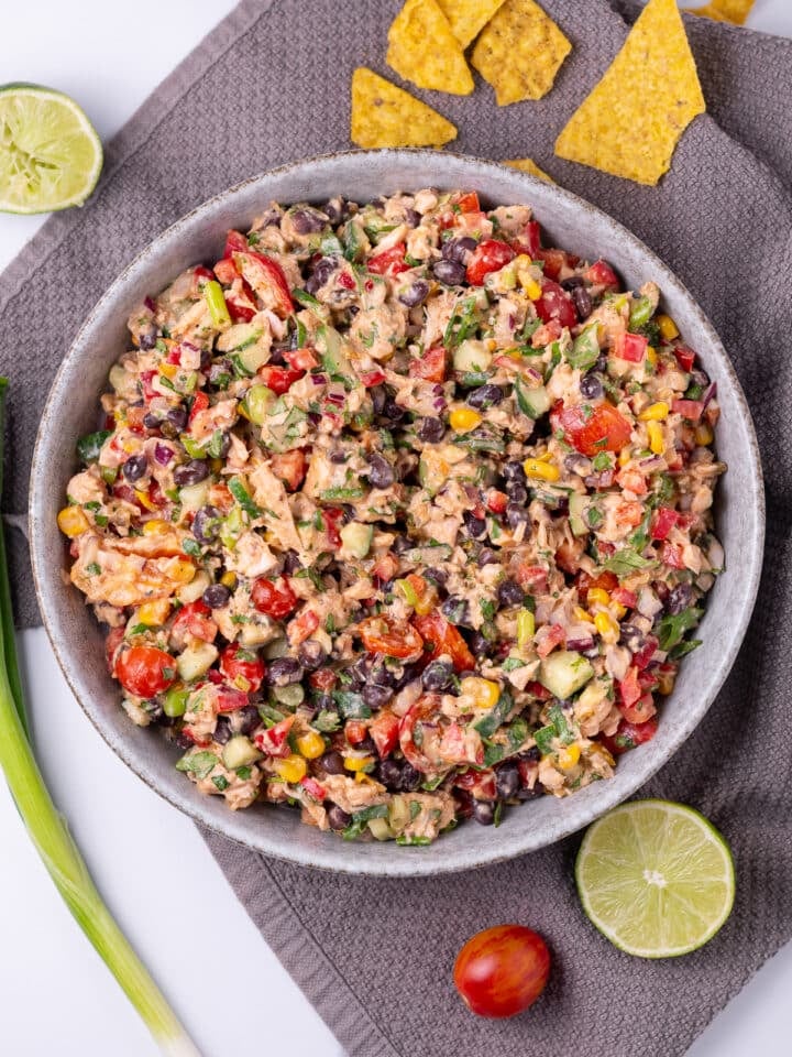 large bowl with mexican tuna salad, gray towel, sliced lime, tortilla chips