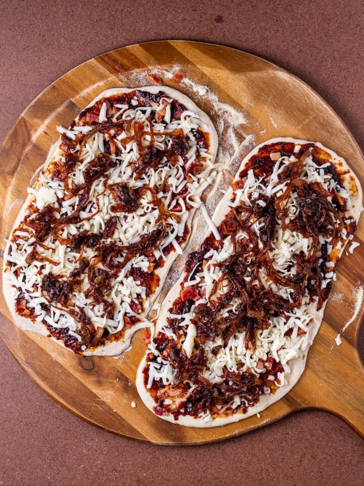 caramelized onions added to flatbreads on a pizza peel