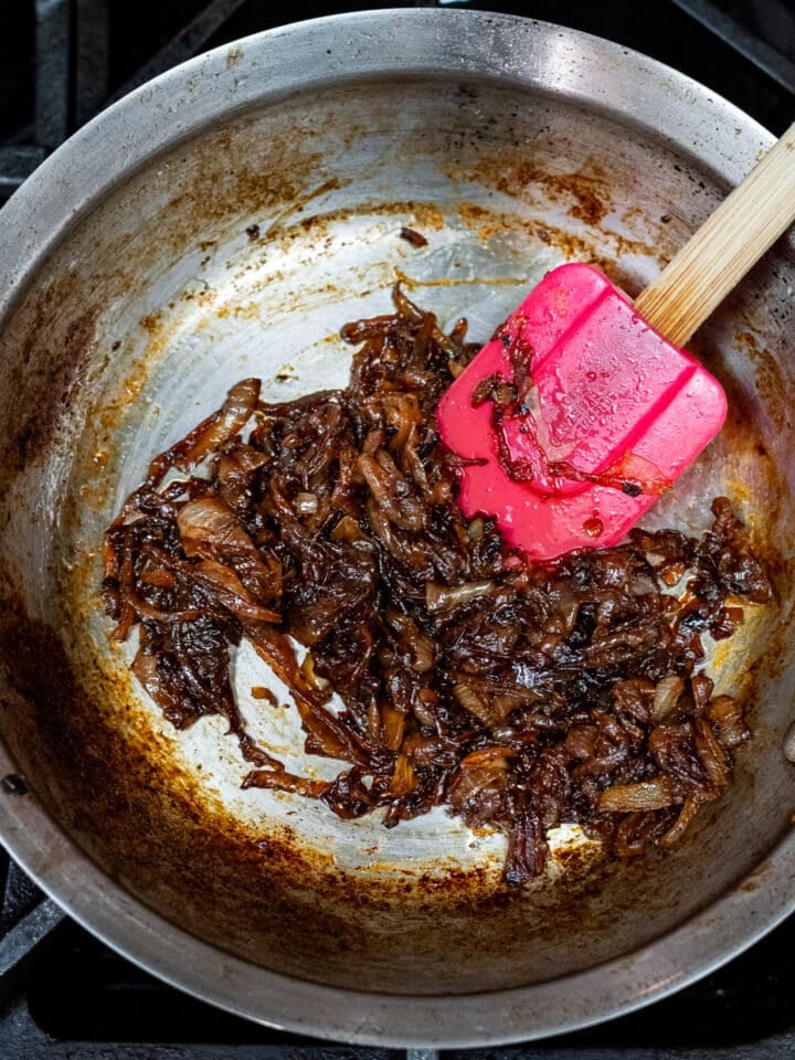 deeply caramelized onions in skillet with a red spatula