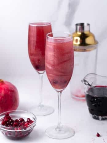 two champagne flutes with pomegranate French 75 cocktail