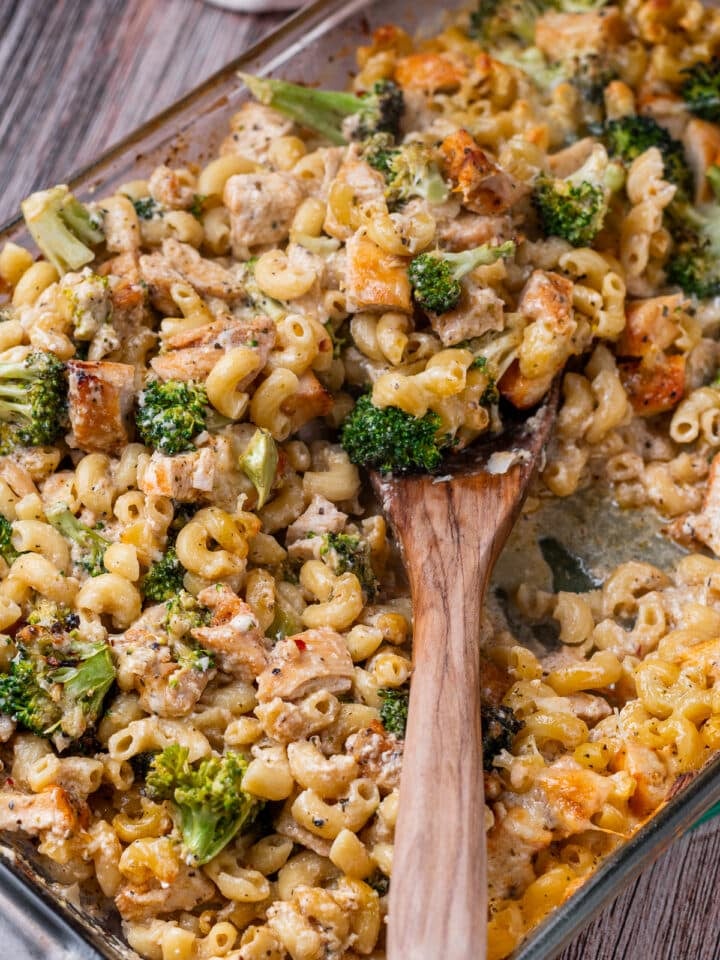 wooden spoon in a casserole dish with chicken and broccoli pasta bake