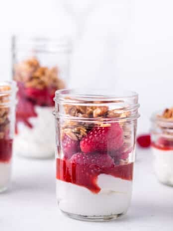 small jar with greek yogurt, raspberry jam, raspberries and granola