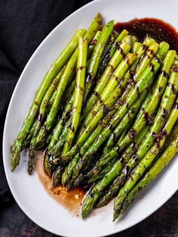 white platter with cooked asparagus and balsamic glaze