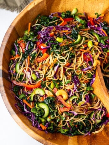 large wooden bowl with rainbow noodles with herbs and cashews