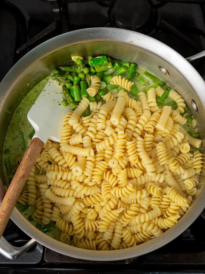 cooked fusilli pasta added to peas, asparagus and creamy pesto sauce