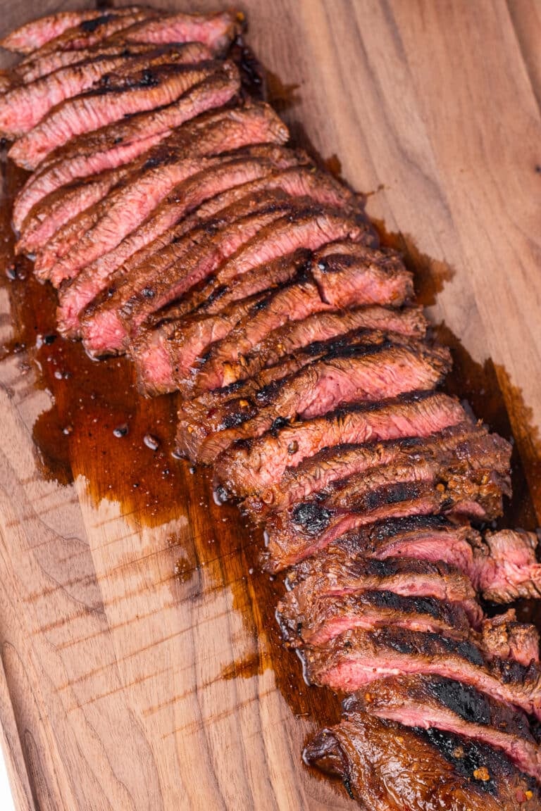 flavorful juices seeping out of a thinly sliced marinated flat iron steak on a wooden cutting board