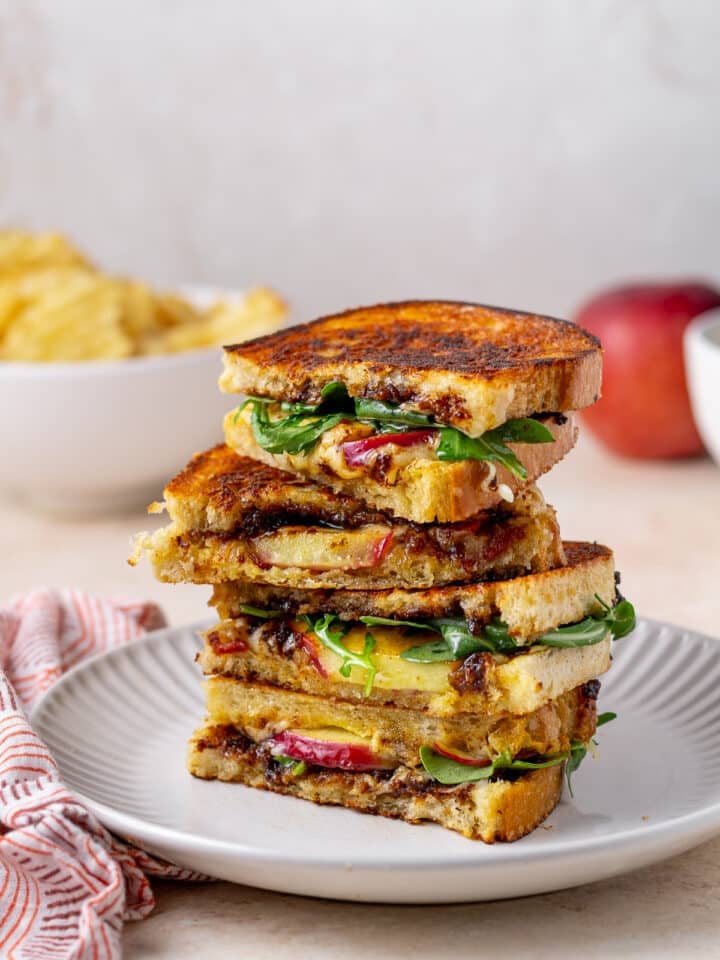 stack of grilled cheese sandwiches with gruyere cheese, arugula, fig jam and apple slices