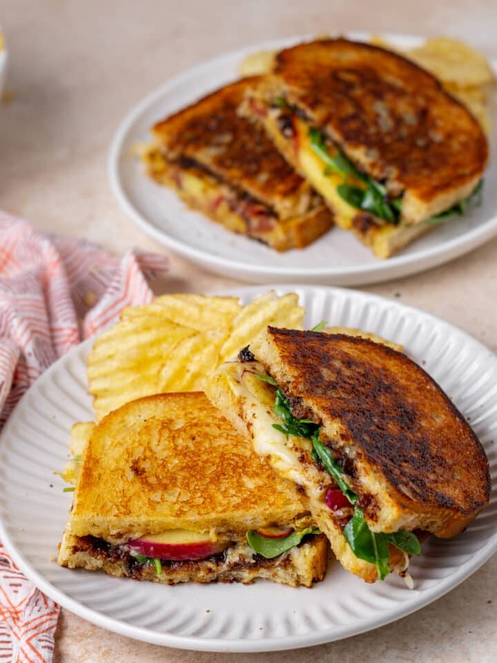 gruyere grilled cheese with apple, fig, bacon and arugula on a plate with potato chips