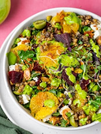 white bowl with beet and lentil salad with mandarin oranges, beets, lentils, parsley dressing, feta, pistachios and crispy shallots