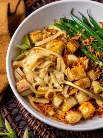 fork twirling curry noodles, crispy tofu cubes and green beans