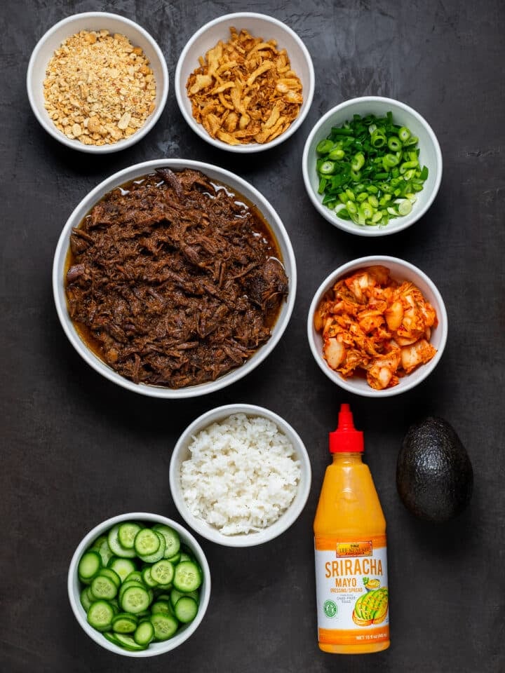 white bowls with various ingredients for a DIY korean shredded beef burrito or rice bowl bar