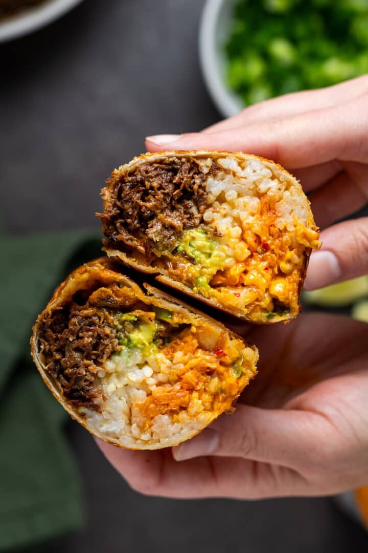 hands holding a burrito made from leftover Korean shredded beef, kimchi, rice, avocado and sriracha mayo
