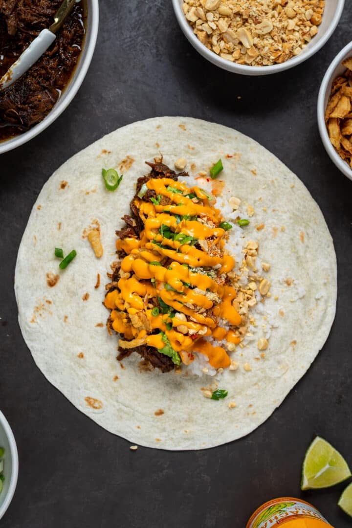 beef, rice, kimchi, green onions and sriracha mayo in a tortilla